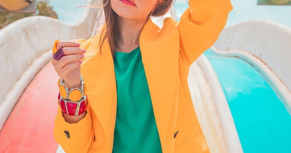 Vibrant fashion photo of a young woman in colorful outfit at outdoor water park, stylish and trendy summer style.