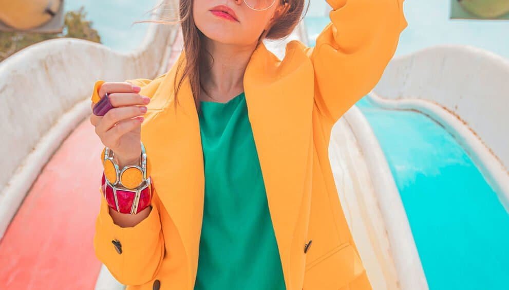 Vibrant fashion photo of a young woman in colorful outfit at outdoor water park, stylish and trendy summer style.