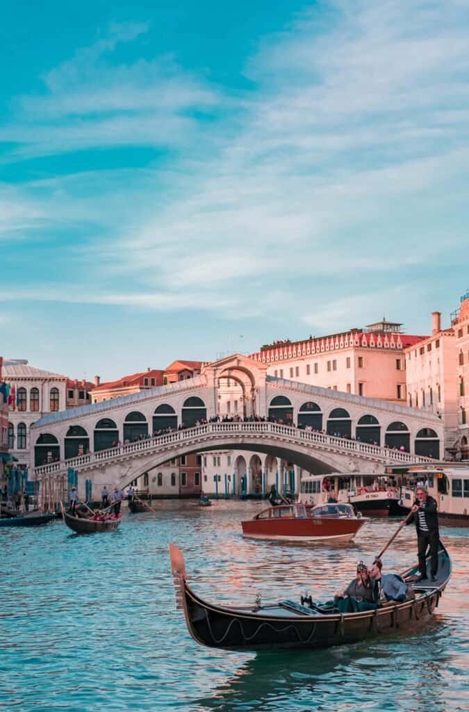 Gondolas on canals in Venice, Italy with historic architecture and blue sky.