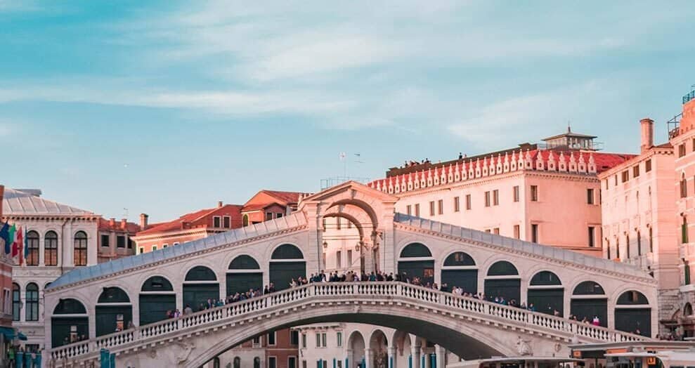 Gondolas on canals in Venice, Italy with historic architecture and blue sky.