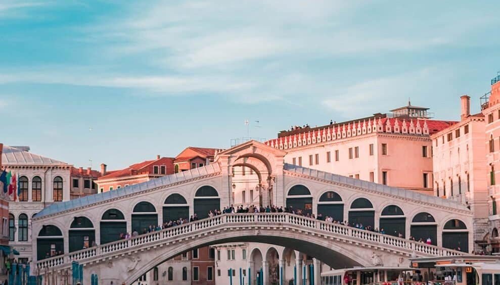Gondolas on canals in Venice, Italy with historic architecture and blue sky.